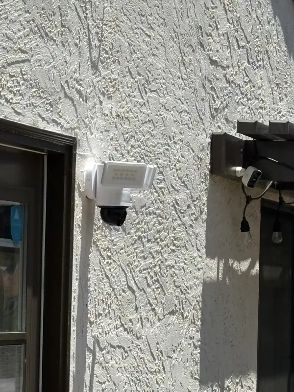 Exterior floodlight camera installed over a doorway
