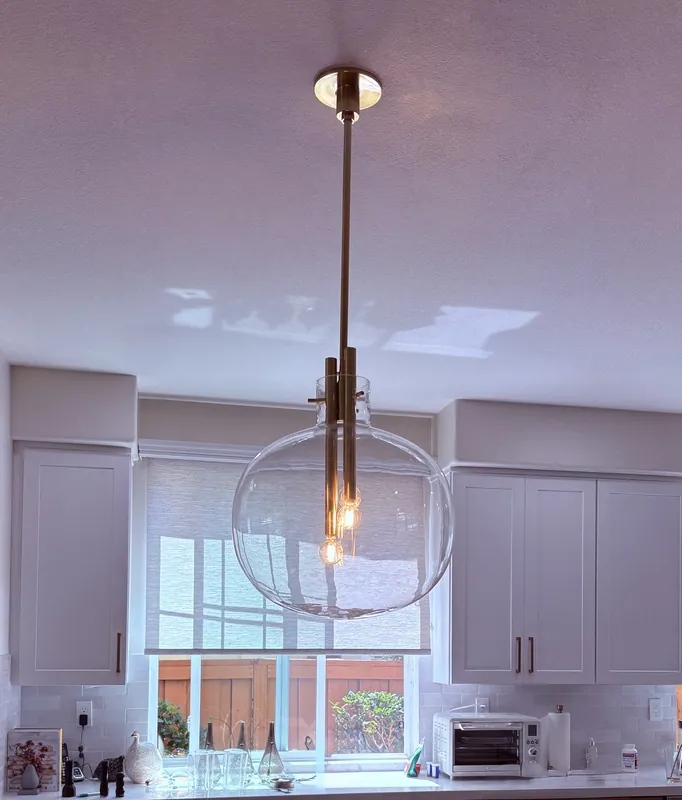 Glass globe pendant light installed over a kitchen sink