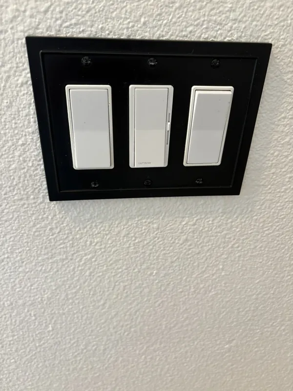 Triple light switch with a black decorative wall plate